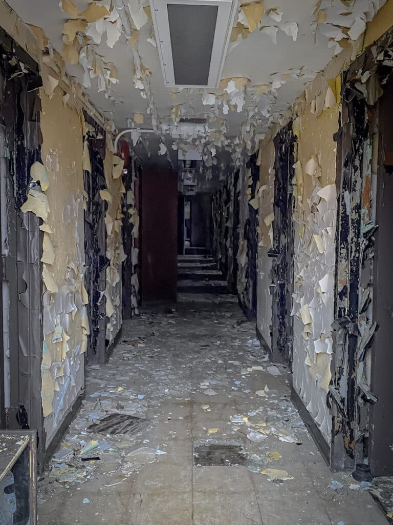 A deserted hallway with yellow peeling paint at The Mid-Orange County Correctional Facility